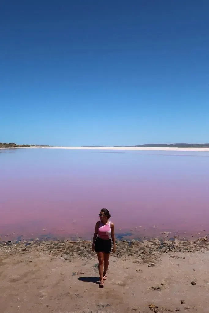 Traveller standing beside the bright pink water of Hutt Lagoon on the Western Australia coast