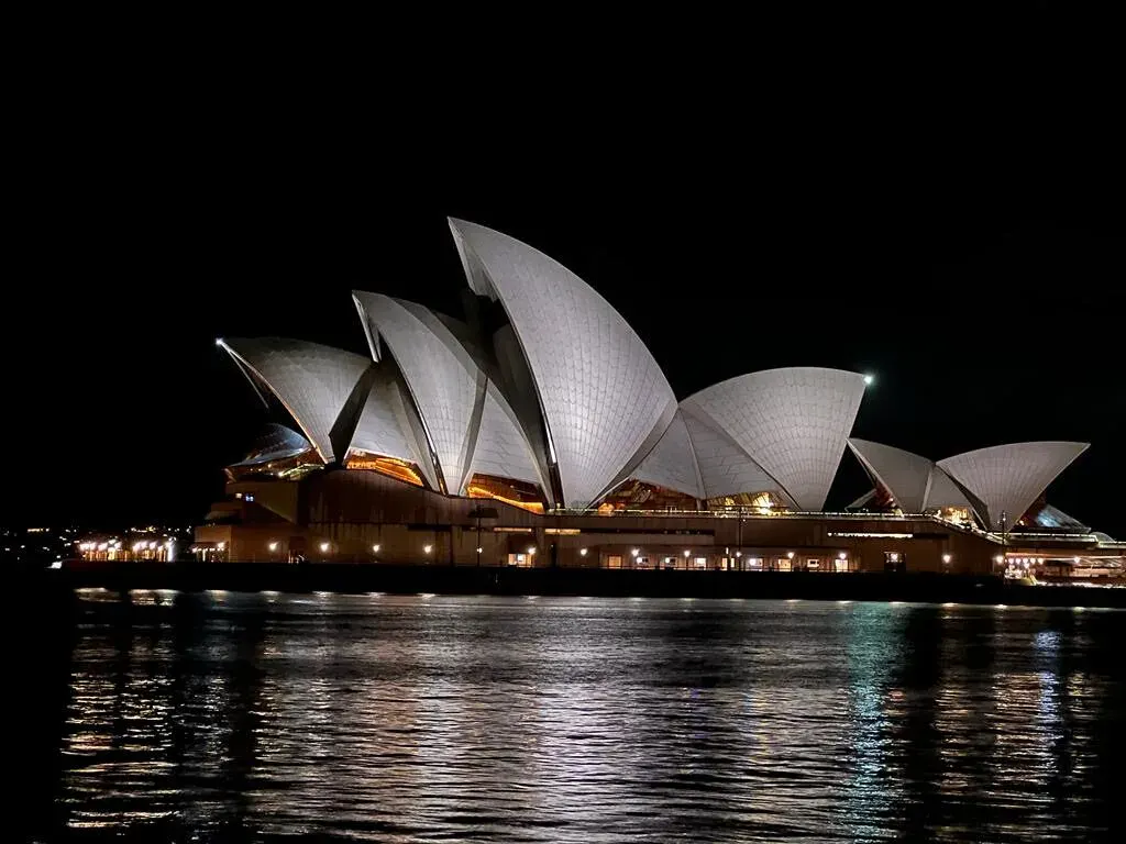 Sydney Opera House lit up at night across the harbour, photographed by a Dundee Adventure traveller