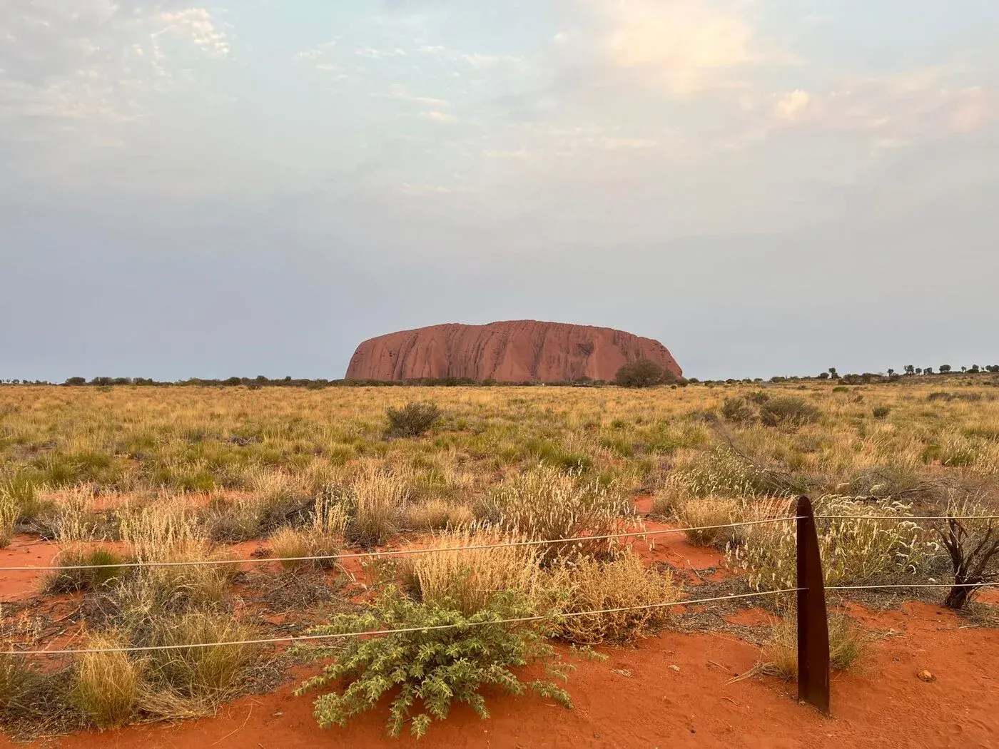 Uluru glowing red at sunset across the spinifex plains, photographed by a Dundee Adventure traveller