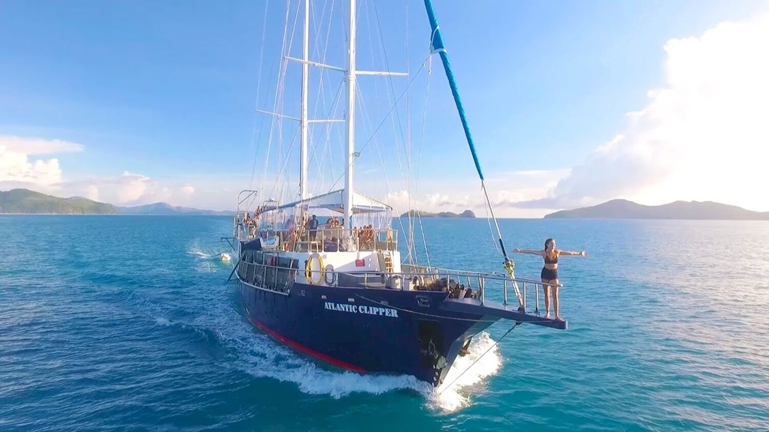 Traveller standing arms-out on the bowsprit of the Atlantic Clipper tall ship sailing the Whitsundays